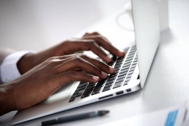 Close-up of hands of african-american businessman typing on a laptop. View through blinds